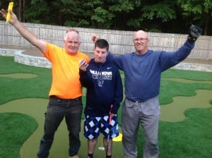 two installers with kid celebrate completion of mini golf course