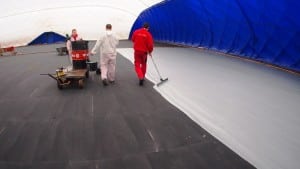 team applies paint to base of hard tennis court