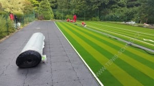 team installs artificial turf onto ultrabasesystems panels for tennis court