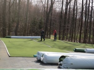 team lays out artificial turf on ultrabasesystems panels next to rolls of turf
