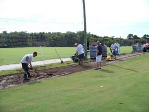 multiple men clear area for turf installation
