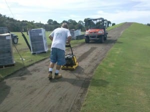 man packing turf area with base panels nearby