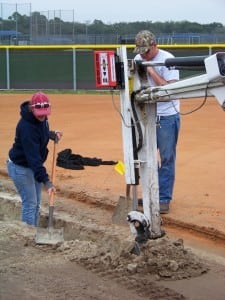 artificial turf field installers dig a trench for base panel system drainage