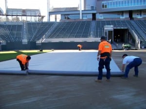 field installers unroll geotextile fabric for football field turf install