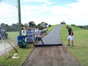 men rolling out geosynthetic fabric for tee line install