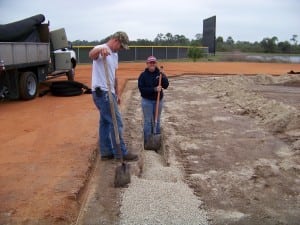 installers place loose gravel over drainage system on empty field