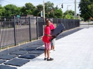 young helpers laying out panels on geotextile for artificial grass installation