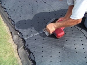 man cutting base panels for tee line turf installation