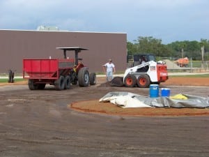 front end loader is excavating turf and dirt from a baseball field