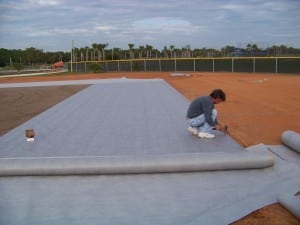 man attaching geo synthetic fabric to dirt floor