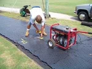 man nailing down base panel system on artificial grass tee line