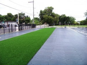 first spool of artificial turf is rolled out on top of base panel system