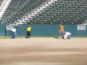 field installers mark edge of football field turf installation with wire