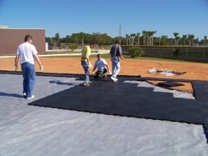 men are installing and walking on base panel system for artificial turf installation