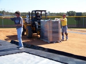 man directing forklift driver with pallet of base panels on field installation