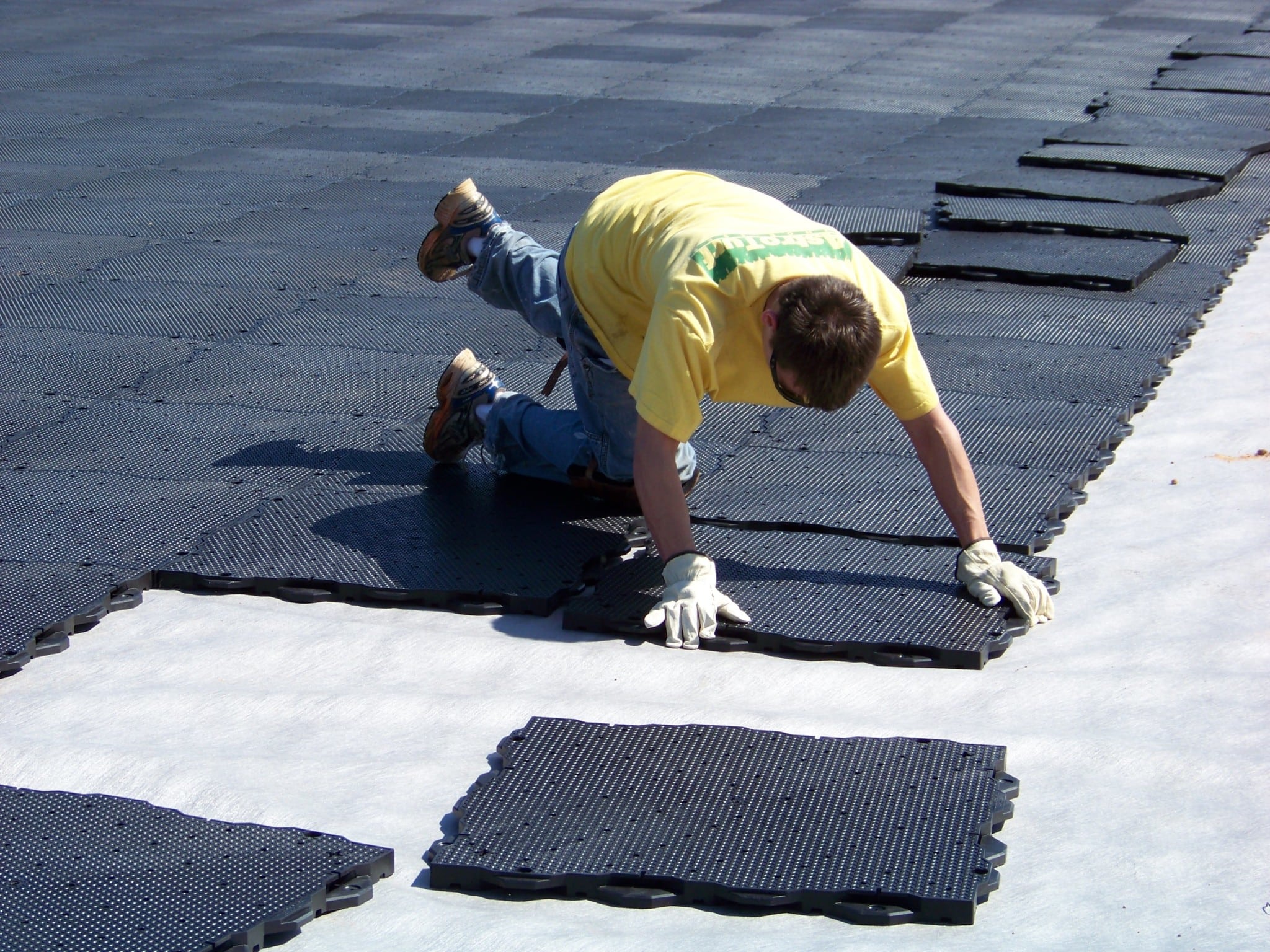 man in gloves assembles base panels for artificial turf installation