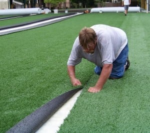 close up shot of man seaming artificial grass together