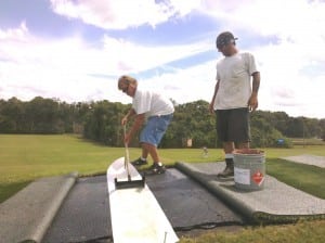 men gluing two pieces of tee line turf together