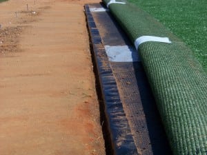 artificial turf is on top of base panel system on dirt field