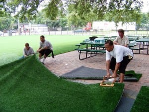 men laying out artificial grass on base panels in tampa soccer installation