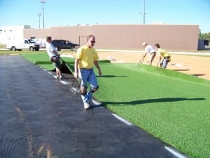laying out artificial turf on top of base panel system during installation