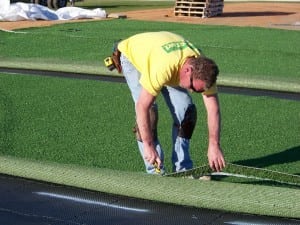 man cutting artificial turf during installation