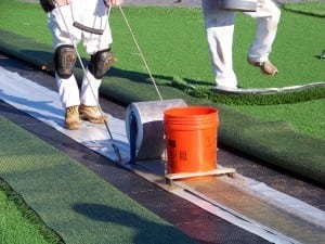 man applying turf adhesive for artificial grass installation