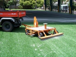 tractor pulling turf rake on newly installed artificial grass with sand infill