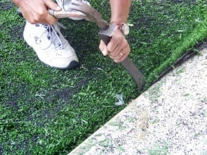 man hammering artificial grass into gap