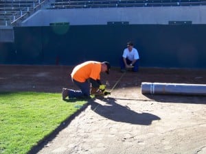 field installers mark edge of football field turf installation with wire