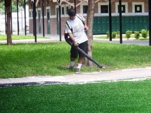man blowing newly installed artificial turf