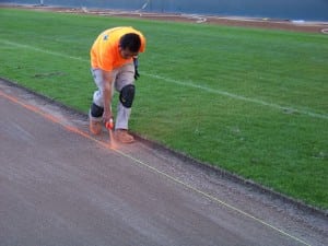 field installer marks line for artificial turf field installation