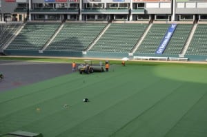 tractor rolling out long pieces of artificial turf on football field