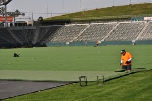 man cutting end of artificial turf on football field