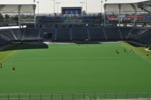full field view of turf applicators seaming artificial turf pieces together on football field