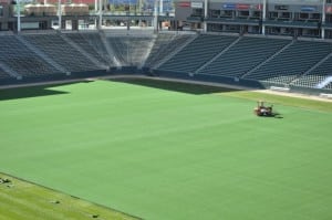 full field view of a tractor applying infill to artificial football field turf