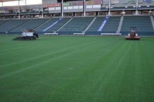 tractors applying infill to artificial football field turf