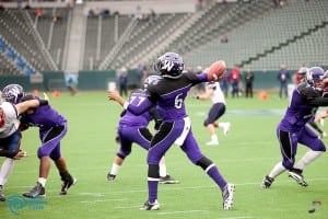 football player in the middle of passing a football during game