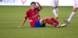 soccer player lying on artificial turf giving a thumbs up