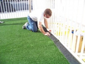 man cutting artificial grass on playground installation