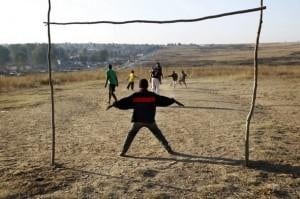 African child guarding soccer goal on dirt field