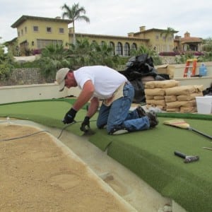 man cutting putting green turf during rooftop installation
