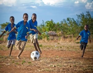 children playing soccer on dirt field