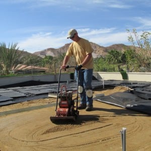 man compacting dirt for rooftop putting green installation