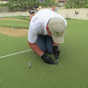 installer cuts artificial turf for roof top golf installation