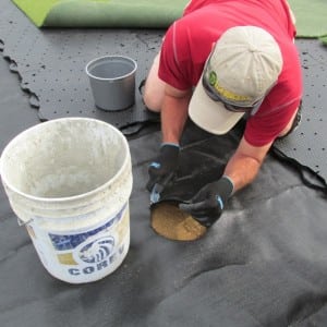 installer cutting geotextile fabric for golf hole installation