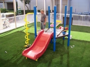 men installing playground equipment on artificial grass