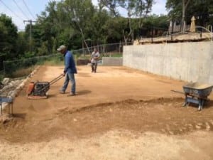 two men flatten a dirt area for basketball court installation