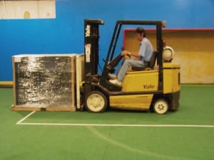 man uses forklift to lift a stack of ultrabasesystems panels for indoor soccer field