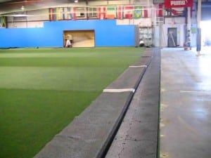 edge of artificial turf mat rolled up near base panels